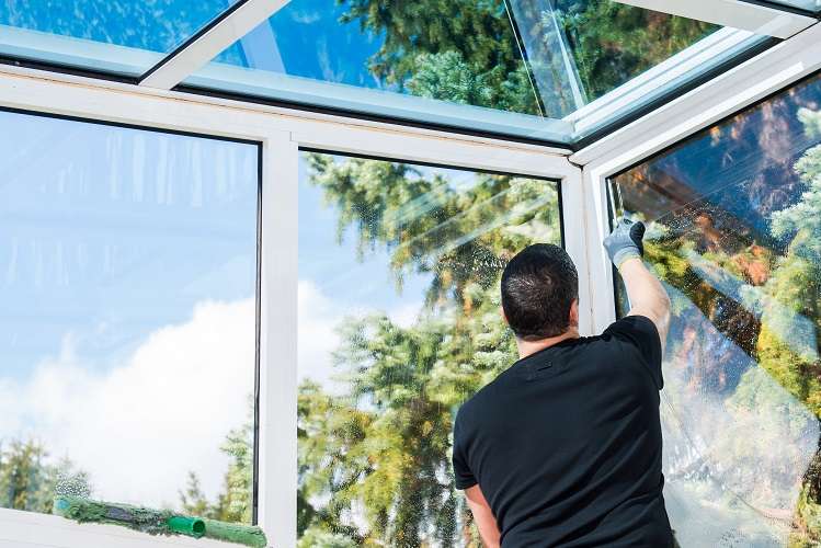 Fensterputzer arbeitet im Wintergarten